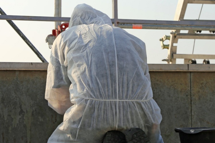 Man In Hazmat Suit Facing Building Testing For Asbestos
